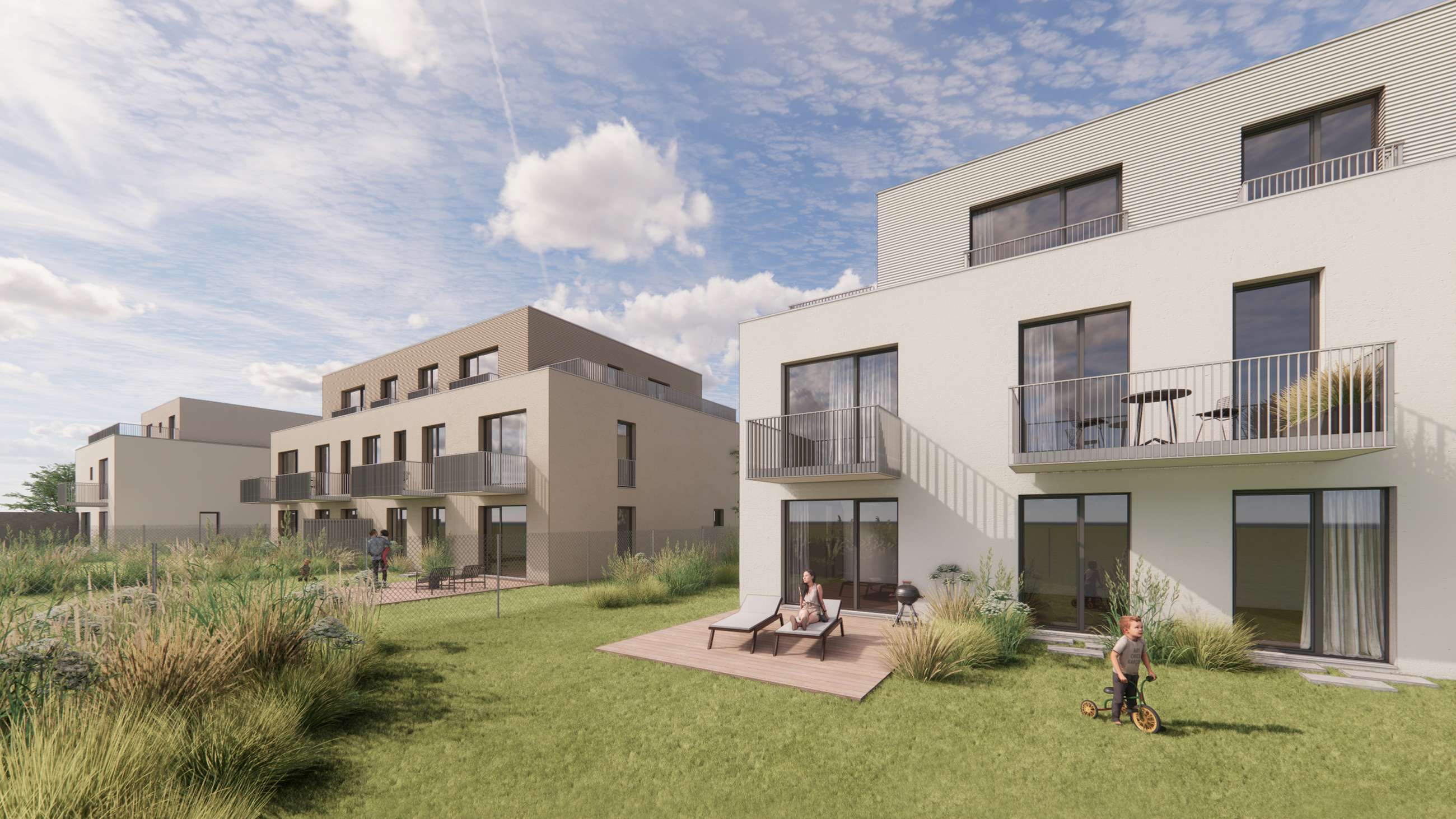 Modern white apartment buildings with balconies and a shared grassy courtyard; a woman on a lounge chair and a child on a small bike on a wooden deck.